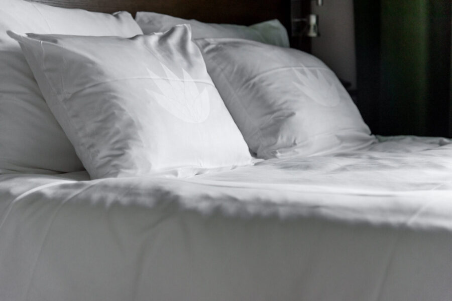 säng bäddad med vita lakan och kuddar