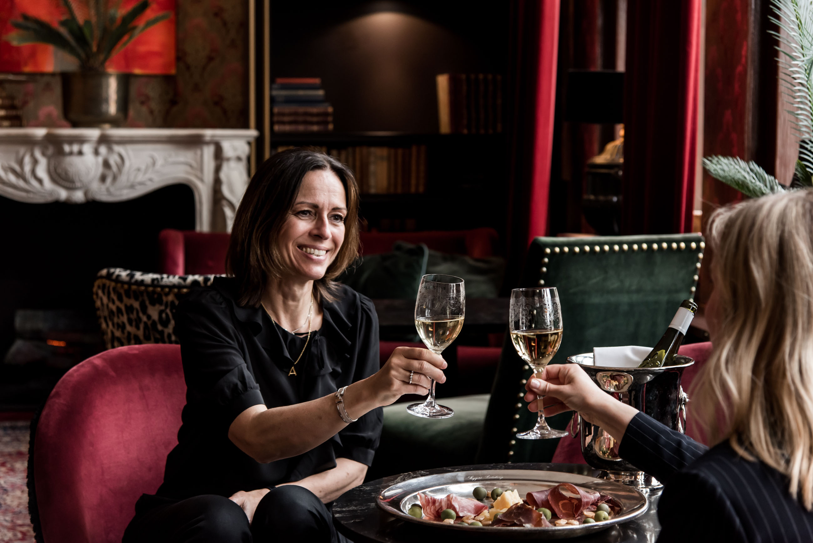 Två kvinnor skålar med vin i lobbyn